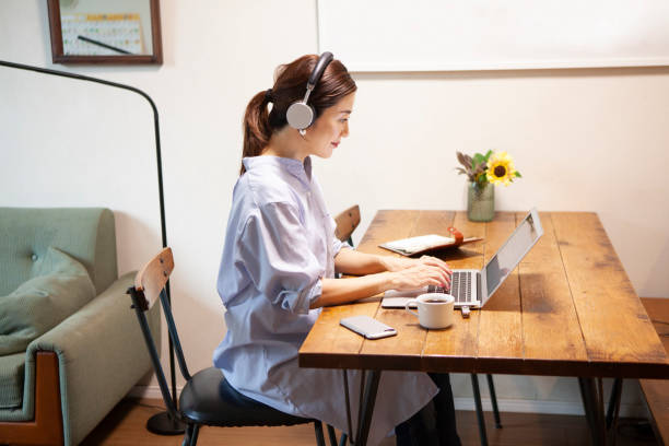 Young working mother is using headphone with computer at her home office